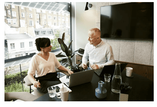  Two people working on laptops at a table.